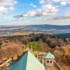 Widok z góry na krajobraz, gdzie są góry świętokrzyskie. Widać lasy, pola i zabudowania.