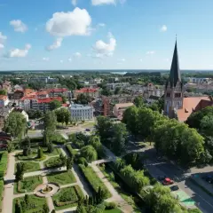Widok na miasto z wieżą kościelną i parkiem. W oddali widać jezioro. Wieża Bismarcka w Szczecinku nie jest widoczna na tym ujęciu.