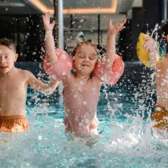 Dzieci bawią się w basenie hotelu z aquaparkiem w górach, chlapiąc wodą i ciesząc się wakacjami.
