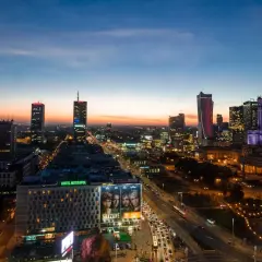 Wieczorna panorama Warszawy, największego miasta w Polsce. Widać Pałac Kultury i Nauki, nowoczesne wieżowce i ruchliwe ulice.