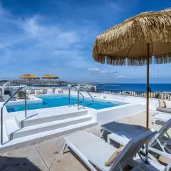 Malta gdzie nocować? Taras z basenem i widokiem na morze, leżaki i parasole. Idealne miejsce na relaks.