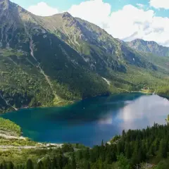 Malowniczy szlak na Morskie Oko prowadzi przez gęsty las do turkusowego jeziora otoczonego skalistymi szczytami Tatr.
