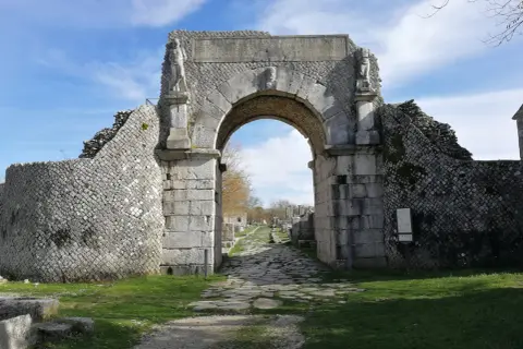 Starożytny łuk w Bojano, z kamienną drogą prowadzącą do ruin.