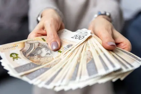 Dłonie trzymające plik banknotów 200 zł. Czy to wynagrodzenie pracownika hotelu?