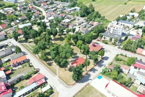 Widok z lotu ptaka na miejscowość Szczuczyn. Domy z czerwonymi dachami, zielone drzewa i pola uprawne.