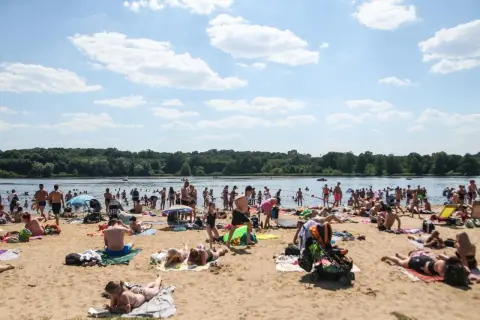 Tłumy ludzi na plaży, cieszące się słońcem i wodą. Idealne miejsce na długie weekendy 2026.