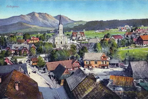 Widok na Zakopane z górami w tle, kościołem i tradycyjnymi willami.