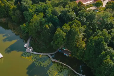 Malownicze jezioro w Torzymiu z żaglówką, drewnianym pomostem i otaczającym lasem.