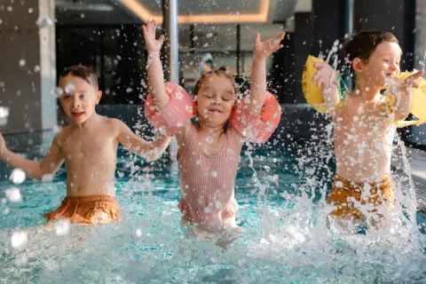 Dzieci bawią się w basenie hotelu z aquaparkiem w górach, chlapiąc wodą i ciesząc się wakacjami.