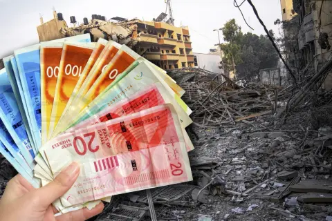 Ręka trzyma banknoty - waluta Izraela, na tle zniszczonego budynku.