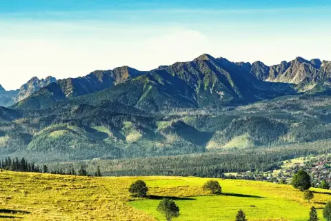 Sierockie widoki na Tatry z zielonymi łąkami i lasami.