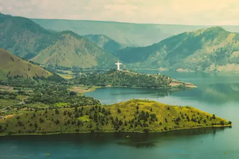 Malownicza wyspa w Indonezji z górami w tle i pomnikiem Chrystusa Króla.