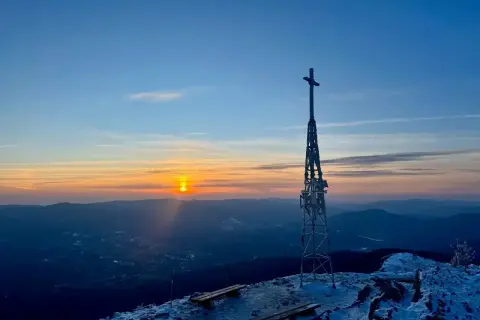 Zachód słońca nad górami, wieża z krzyżem i ławki na szczycie. Smerek szlak zaprasza na zimowy spacer.