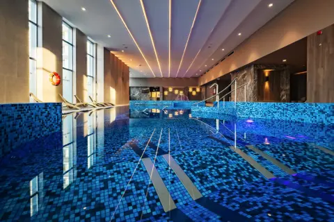 Luksusowy basen w hotelu 5 gwiazdkowym nad morzem. Błękitne płytki, leżaki i światło tworzą relaksującą atmosferę.