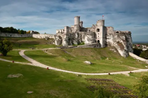 Ruiny zamku Olsztyn k Częstochowy na wapiennym wzgórzu, z polami i lasami w tle.