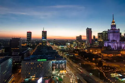 Wieczorna panorama Warszawy, największego miasta w Polsce. Widać Pałac Kultury i Nauki, nowoczesne wieżowce i ruchliwe ulice.
