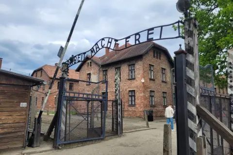 Brama z napisem "Arbeit Macht Frei" prowadzi do budynków obozu Auschwitz.