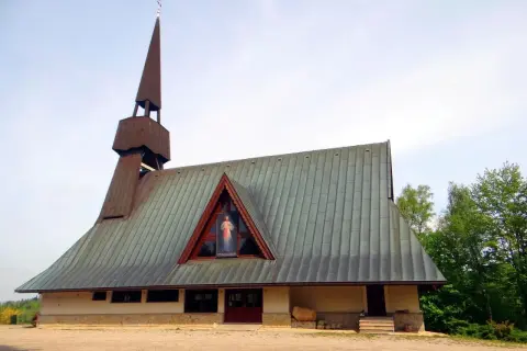 Nowoczesny kościół w Jamnej z charakterystyczną wieżą i dachem. W trójkątnym okapie widnieje obraz Jezusa Miłosiernego.
