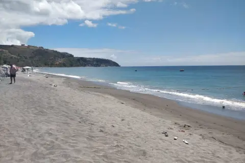 Piękna plaża na wyspie Dominika. Ciemny piasek, turkusowe morze i zielone wzgórza w tle. Idealne miejsce na relaks.