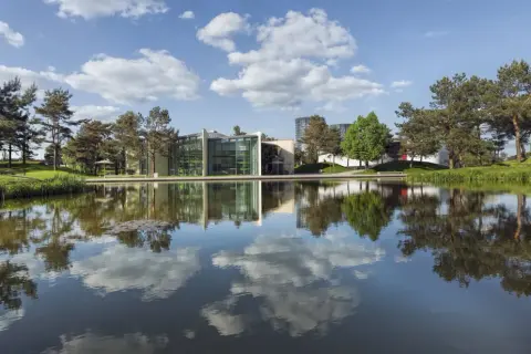 Nowoczesne budynki z zielonymi akcentami odbijają się w spokojnej tafli wody. To malownicze **Wolfsburg miasto**, gdzie natura harmonijnie współgra z architekturą.