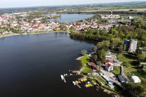 Widok na miasteczko nad jeziorem, gdzie mogłyby się odbyć **blue moon kuchenne rewolucje**. Widać łódki, budynki i zieleń.