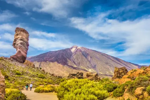 Wulkan Teide na Teneryfie, idealna pogoda w październiku. Skalny palec i para spacerująca pośród zieleni.