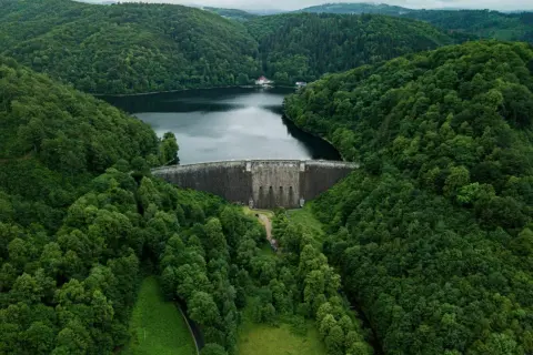 Majestatyczna zapora wodna otoczona bujną zielenią, tworząca jedno z malowniczych jezior na Dolnym Śląsku.