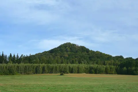 Zielone wzgórze porośnięte lasem, przypominające wygasłe wulkany w Polsce.
