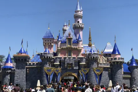 Bajkowy zamek z niebieskimi dachami, jak w Disneylandzie w Polsce. Tłum ludzi przed wejściem.