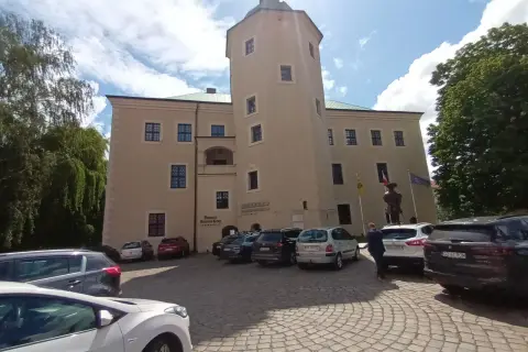 Zamek w Redzikowie, z wieżą i parkingiem przed wejściem.