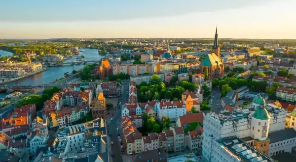 Widok z lotu ptaka na piękne Stare Miasto w Szczecinie, gdzie rzeka Odra przepływa przez miasto, a słońce zachodzi nad zabytkowymi budynkami.
