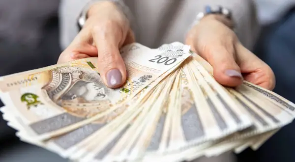 Dłonie trzymające plik banknotów 200 zł. Czy to wynagrodzenie pracownika hotelu?