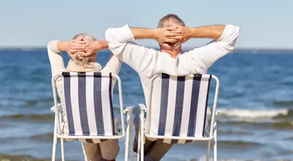 Para emerytów cieszy się słońcem na plaży. Idealne wczasy dla emerytów z dojazdem, relaks nad wodą.