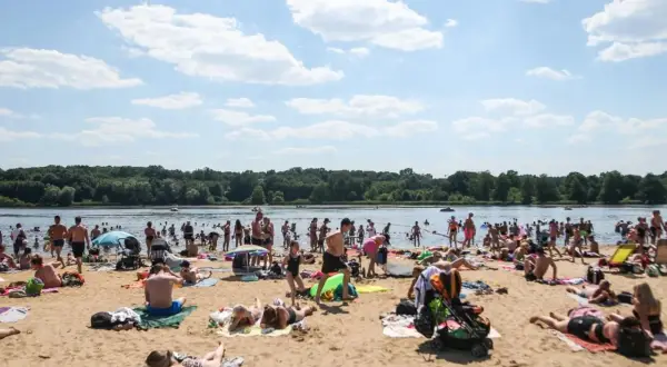 Tłumy ludzi na plaży, cieszące się słońcem i wodą. Idealne miejsce na długie weekendy 2026.