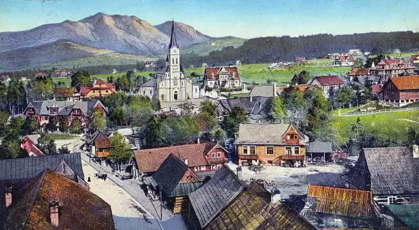 Widok na Zakopane z górami w tle, kościołem i tradycyjnymi willami.