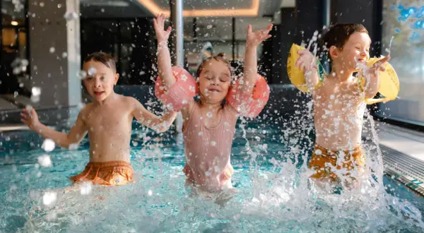 Dzieci bawią się w basenie hotelu z aquaparkiem w górach, chlapiąc wodą i ciesząc się wakacjami.