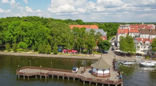 Idealny weekend na Mazurach: malownicza promenada, urokliwa przystań i uśmiechnięci ludzie cieszący się słońcem.