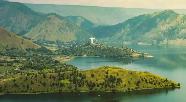 Malownicza wyspa w Indonezji z górami w tle i pomnikiem Chrystusa Króla.