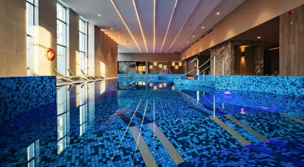 Luksusowy basen w hotelu 5 gwiazdkowym nad morzem. Błękitne płytki, leżaki i światło tworzą relaksującą atmosferę.