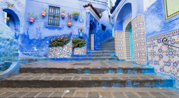 Niebieskie miasto w Maroku, Chefchaouen, zachwyca kolorowymi mozaikami i kwitnącymi roślinami.