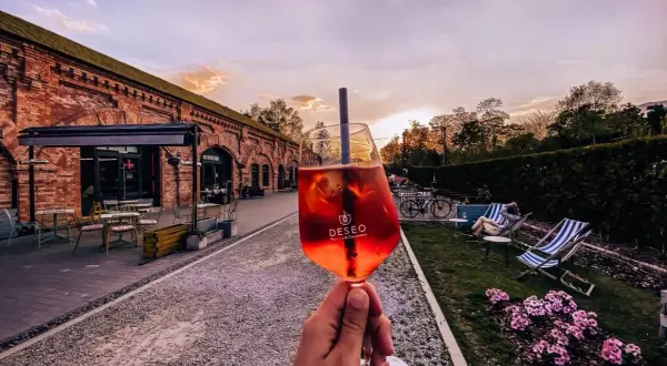 Nietypowe restauracje Warszawa: drink w ręce, ceglany budynek i ogród z leżakami. Idealne miejsce na relaks.