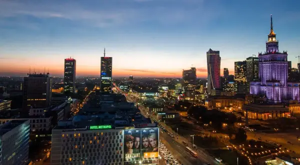 Wieczorna panorama Warszawy, największego miasta w Polsce. Widać Pałac Kultury i Nauki, nowoczesne wieżowce i ruchliwe ulice.