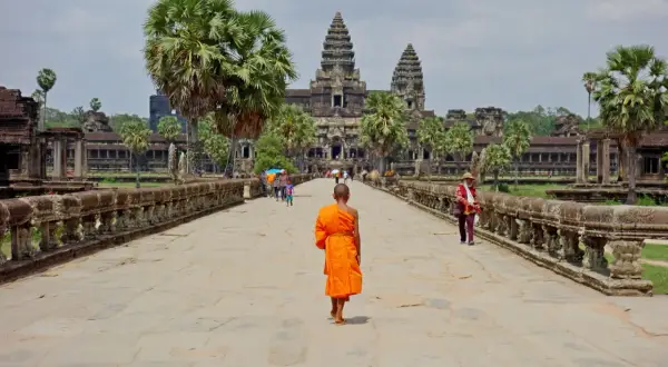 Mnich w pomarańczowej szacie idzie do Angkor Wat, wspaniałego miejsca na kambodżańskie wakacje.