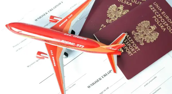 Czerwony samolot i dwa polskie paszporty leżą na wniosku urlopowym. Czy do Albanii potrzebny jest paszport? Sprawdź przed podróżą!