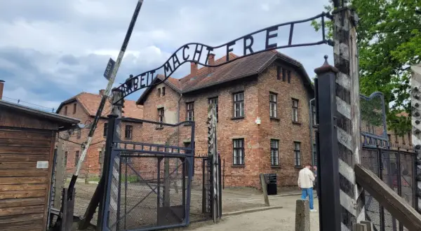 Brama z napisem "Arbeit Macht Frei" prowadzi do budynków obozu Auschwitz.