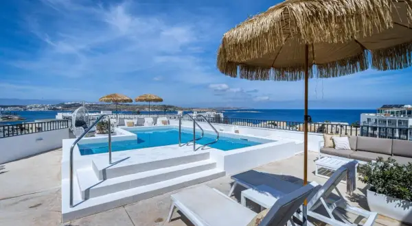 Malta gdzie nocować? Taras z basenem i widokiem na morze, leżaki i parasole. Idealne miejsce na relaks.