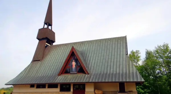 Nowoczesny kościół w Jamnej z charakterystyczną wieżą i dachem. W trójkątnym okapie widnieje obraz Jezusa Miłosiernego.