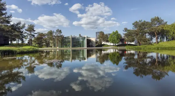 Nowoczesne budynki z zielonymi akcentami odbijają się w spokojnej tafli wody. To malownicze **Wolfsburg miasto**, gdzie natura harmonijnie współgra z architekturą.
