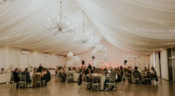 Elegancka sala bankietowa z żyrandolami i światełkami, idealna do organizacji wyjazdów na konferencje i wycieczki firmowe.