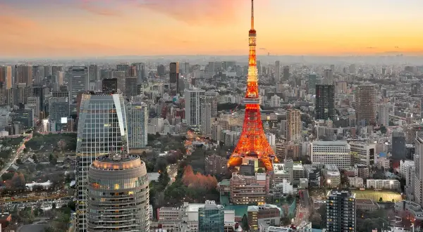 Widok na Tokio z wieżą Tokyo Tower w pomarańczowych barwach o zachodzie słońca. Tysiące budynków, które świadczą o tym, ile ludzi mieszka w Tokio.